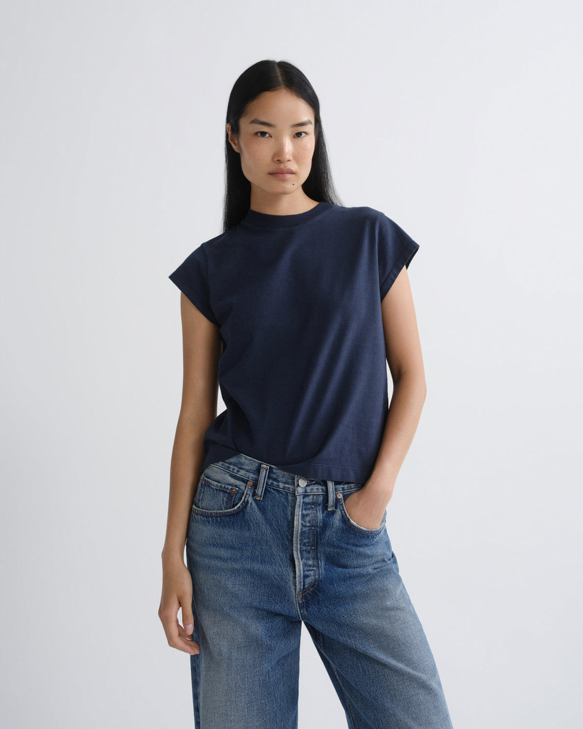 Person wearing a navy blue t-shirt and blue jeans on a white background