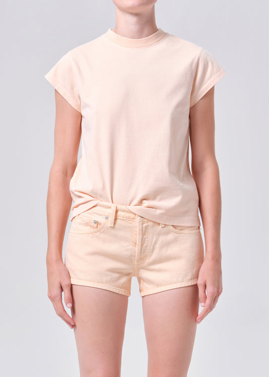 Person wearing a matching peach t-shirt and shorts set on a light gray background