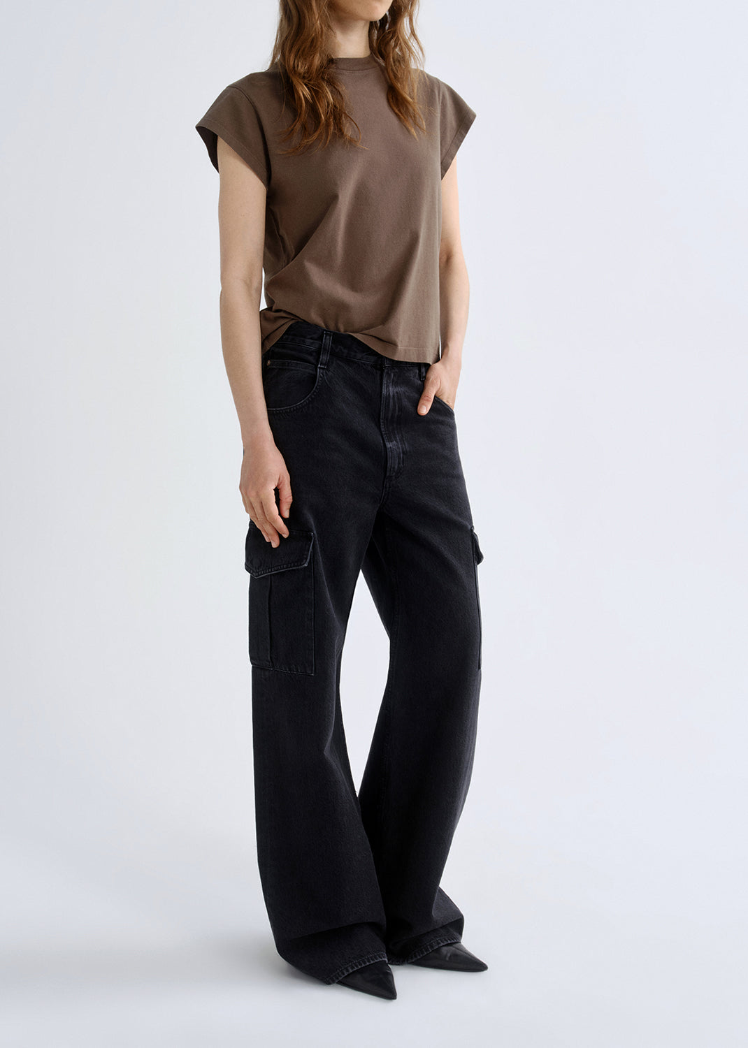 Person wearing a brown t-shirt and black cargo pants on a grey background