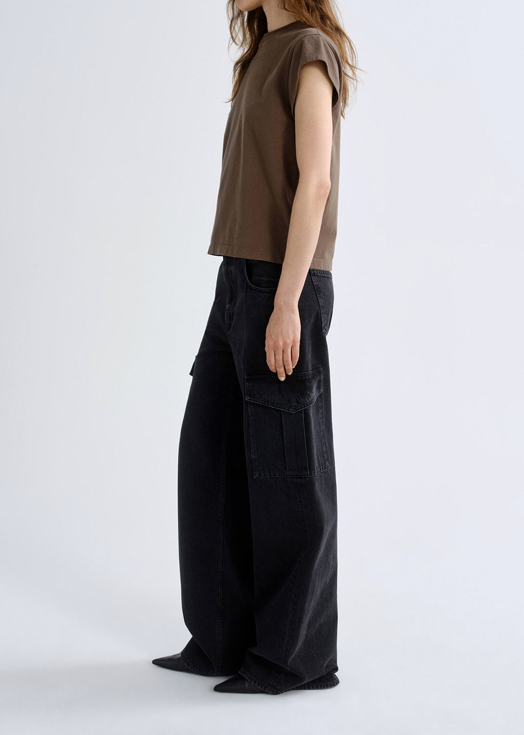 Person wearing a brown sleeveless top and black wide-leg pants on a grey background