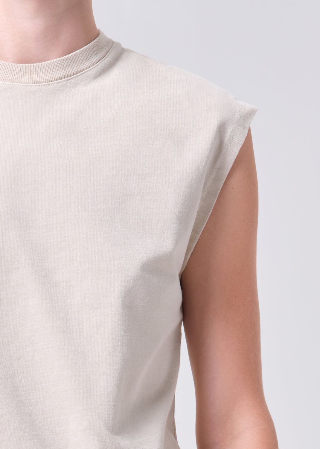 Beige sleeveless top worn by a person on a light gray background