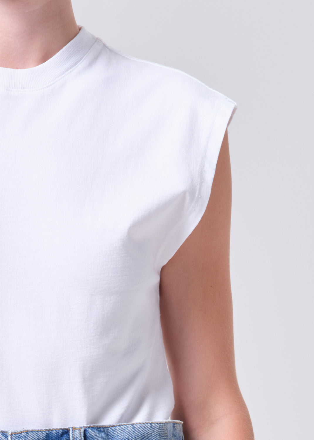 White sleeveless top worn by a person on a plain background