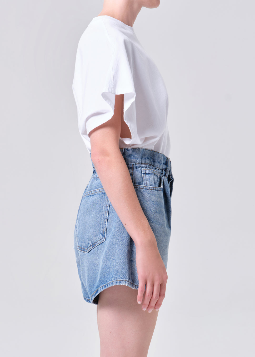 Person wearing a white t-shirt and denim skirt on a plain background