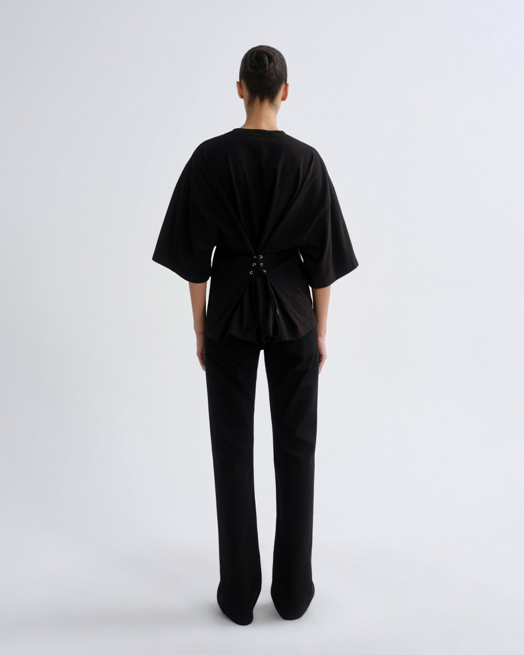 Person wearing a black outfit with a draped design on a white background