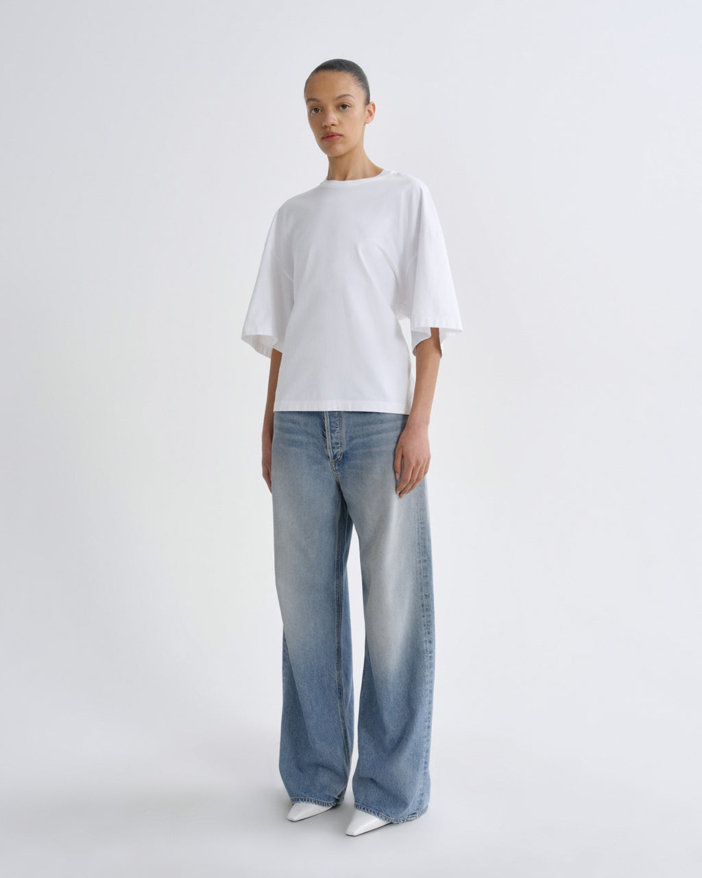 Person wearing a white t-shirt and blue jeans on a white background