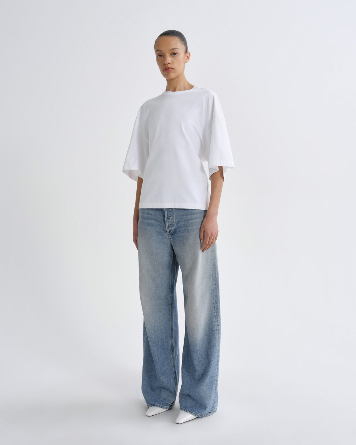 Person wearing a white t-shirt and blue jeans on a white background