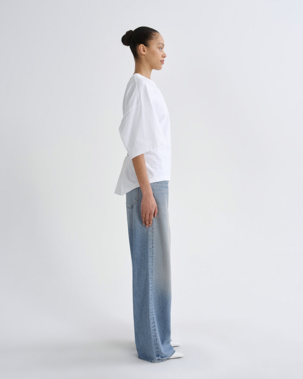 Person wearing a white shirt and light blue jeans on a white background
