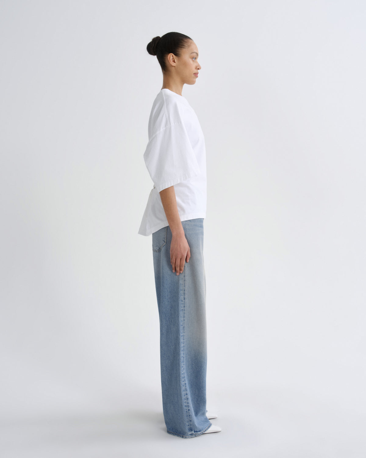 Person wearing a white shirt and light blue jeans on a white background