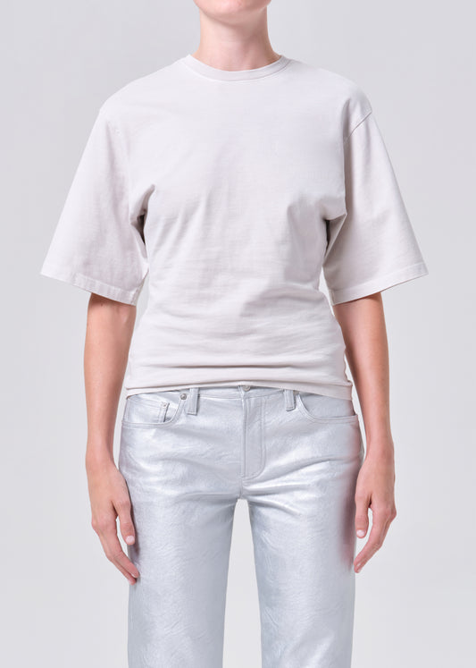 Person wearing a plain white t-shirt and light blue jeans on a gray background