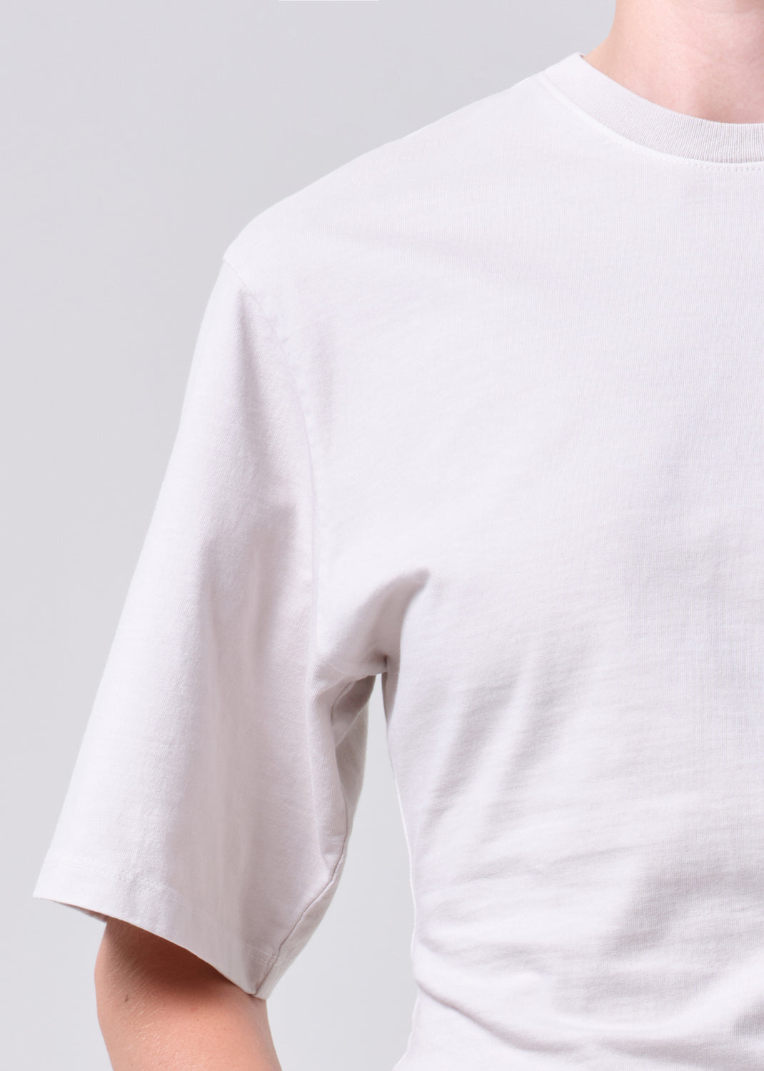 White t-shirt worn by a person on a light gray background