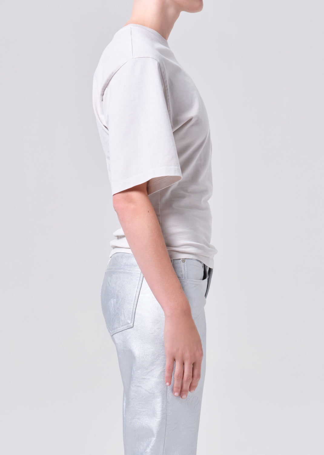 Person wearing a light gray t-shirt and pants on a white background