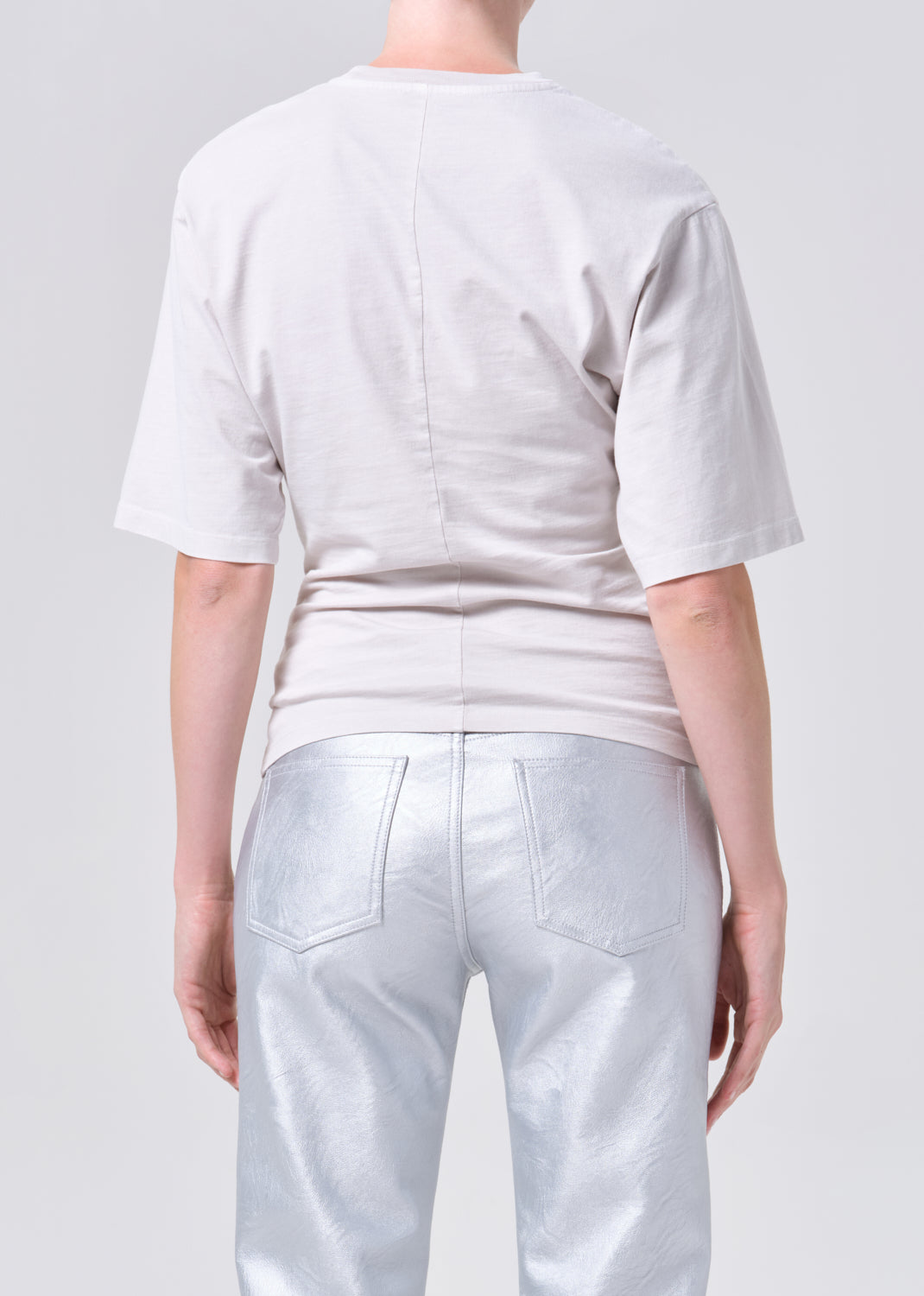 Person wearing a light gray t-shirt and pants on a plain background