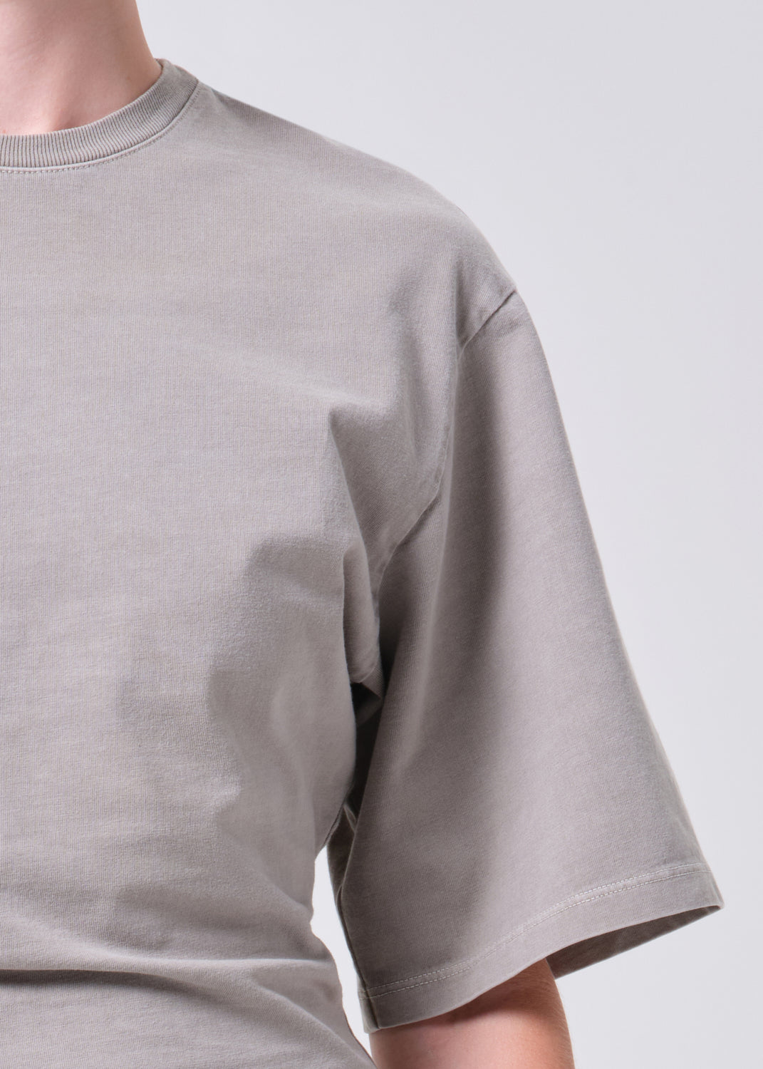 Gray t-shirt worn by a person on a plain background