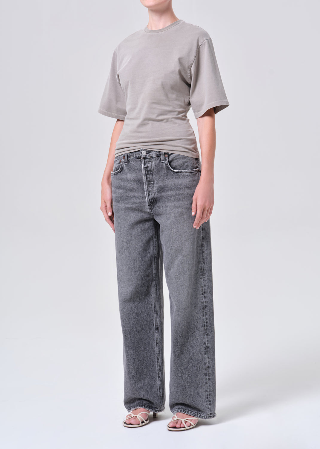 Person wearing a gray t-shirt and blue jeans on a white background