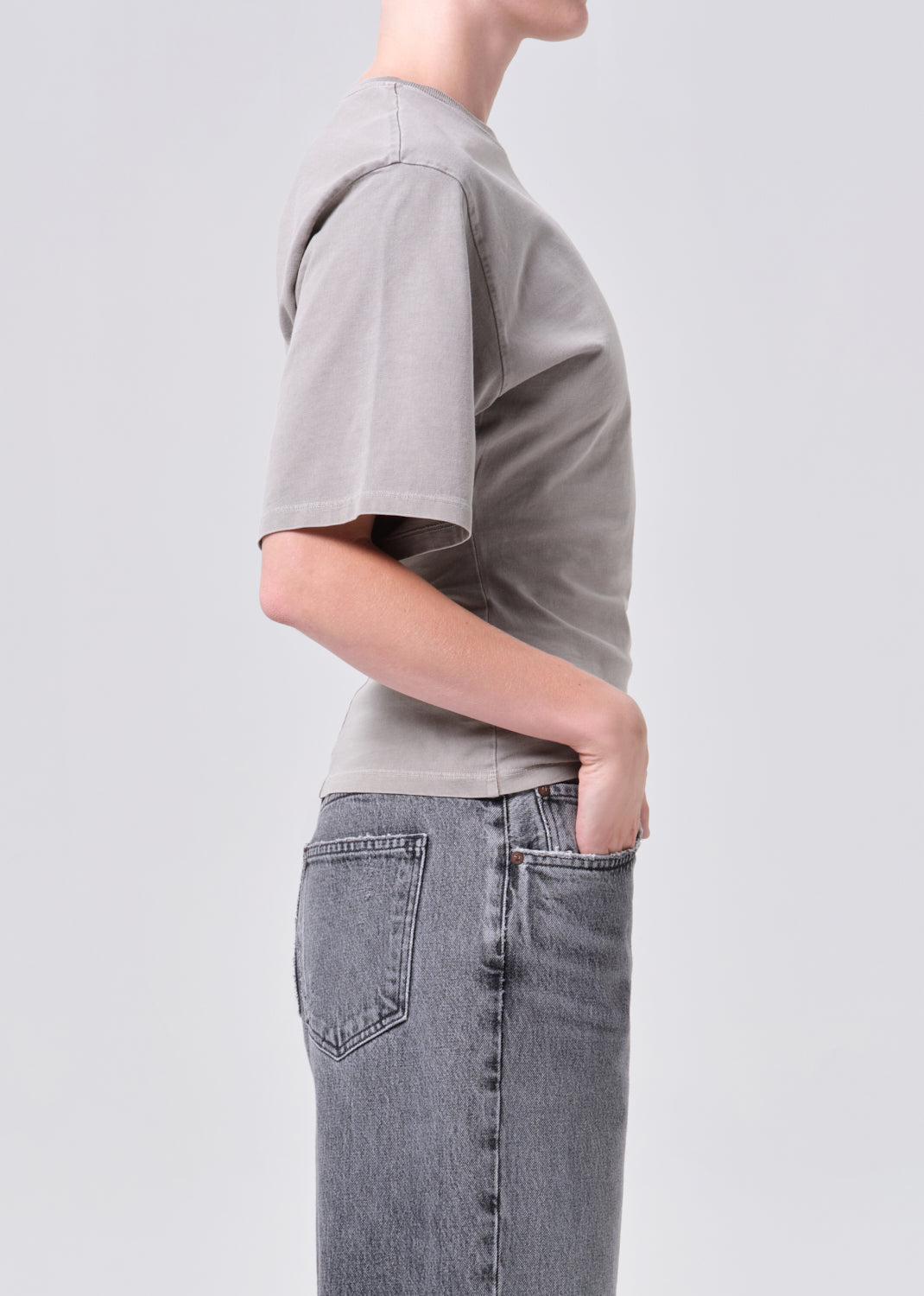Person wearing a gray t-shirt and jeans on a plain background