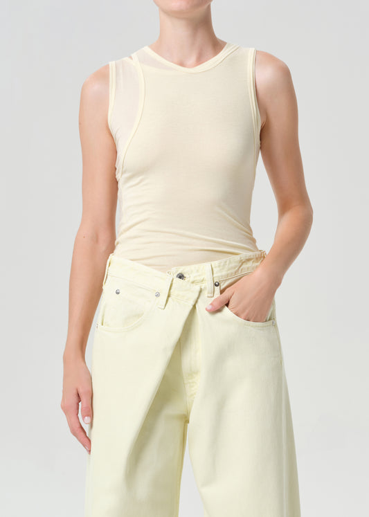 Person wearing a light-colored sleeveless top and wide-leg pants on a plain background
