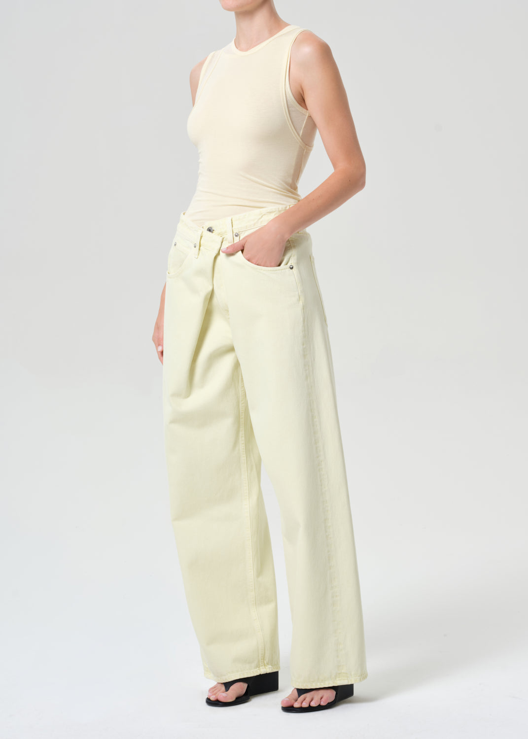Person wearing a light-colored sleeveless top and wide-leg pants on a white background