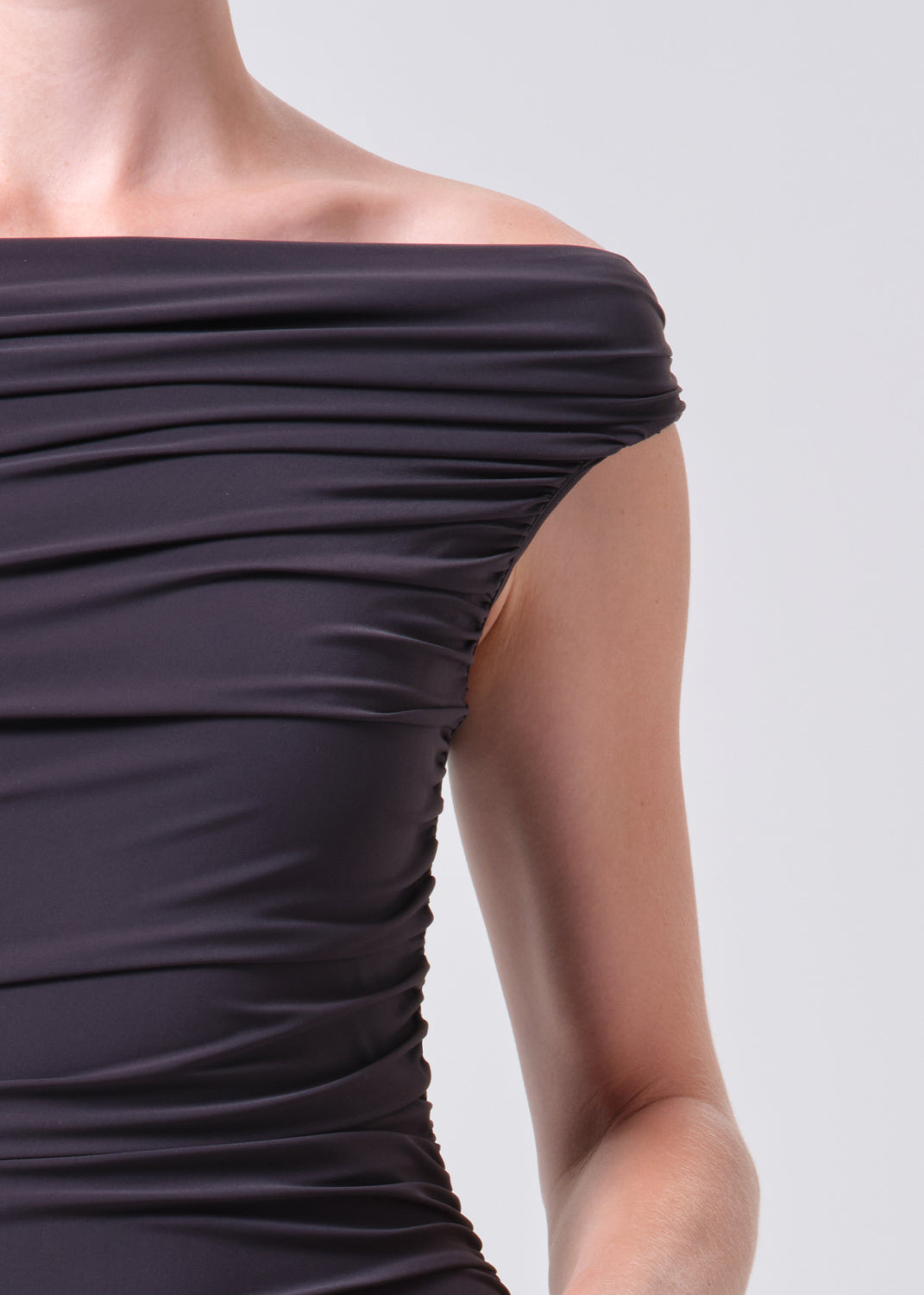 Close-up of a dark purple off-shoulder top on a plain background