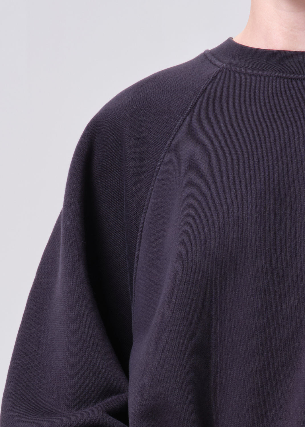Close-up of a dark purple sweatshirt on a light gray background