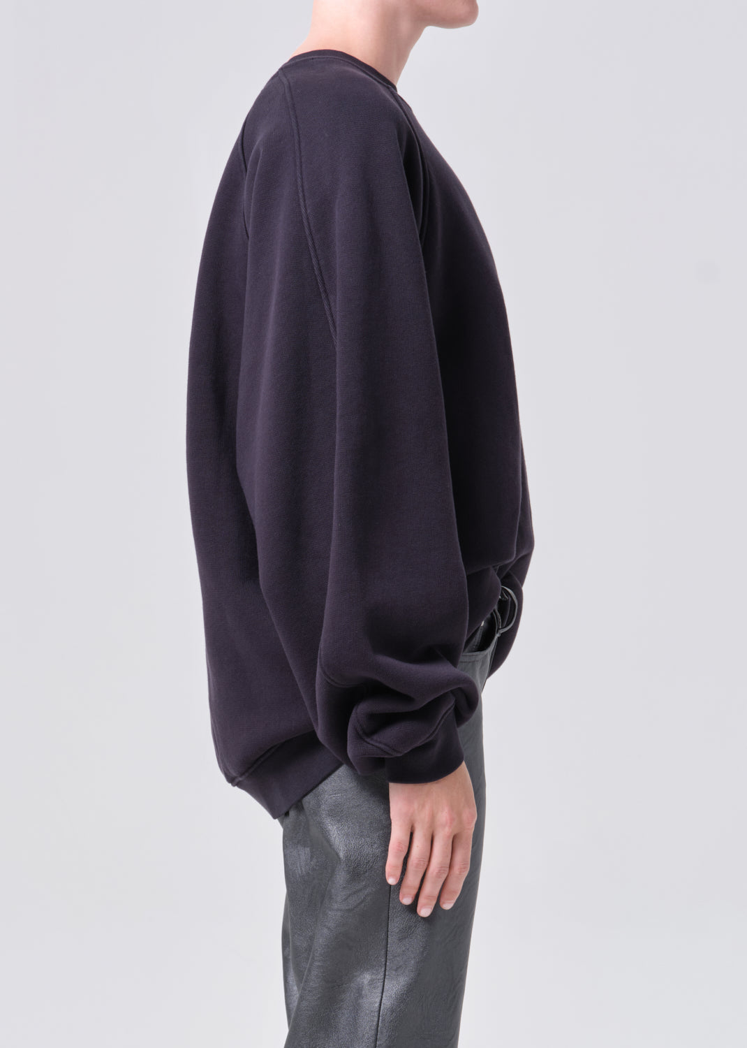 Person wearing a black oversized sweatshirt on a light gray background