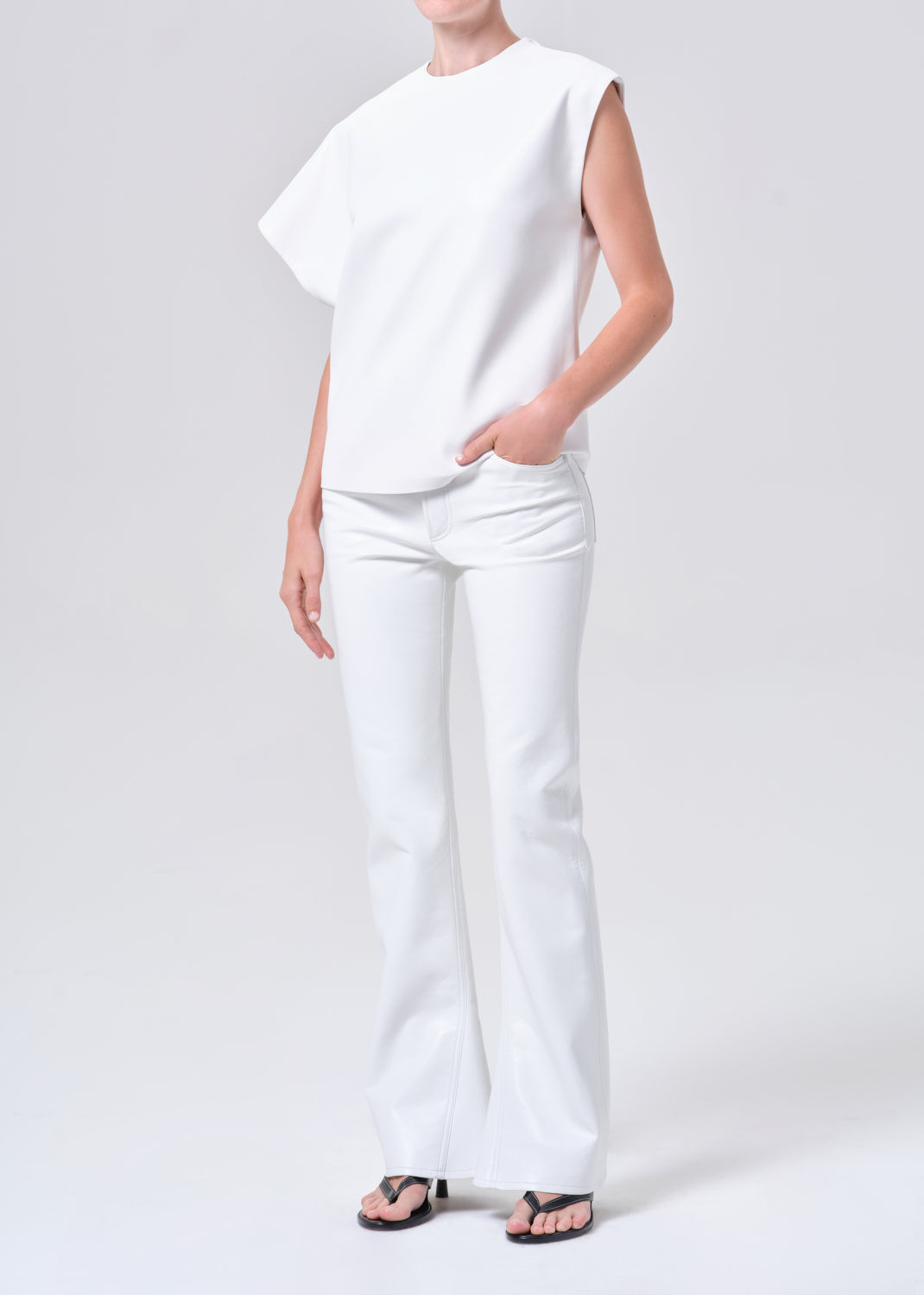 Person wearing a white sleeveless top and pants on a light gray background