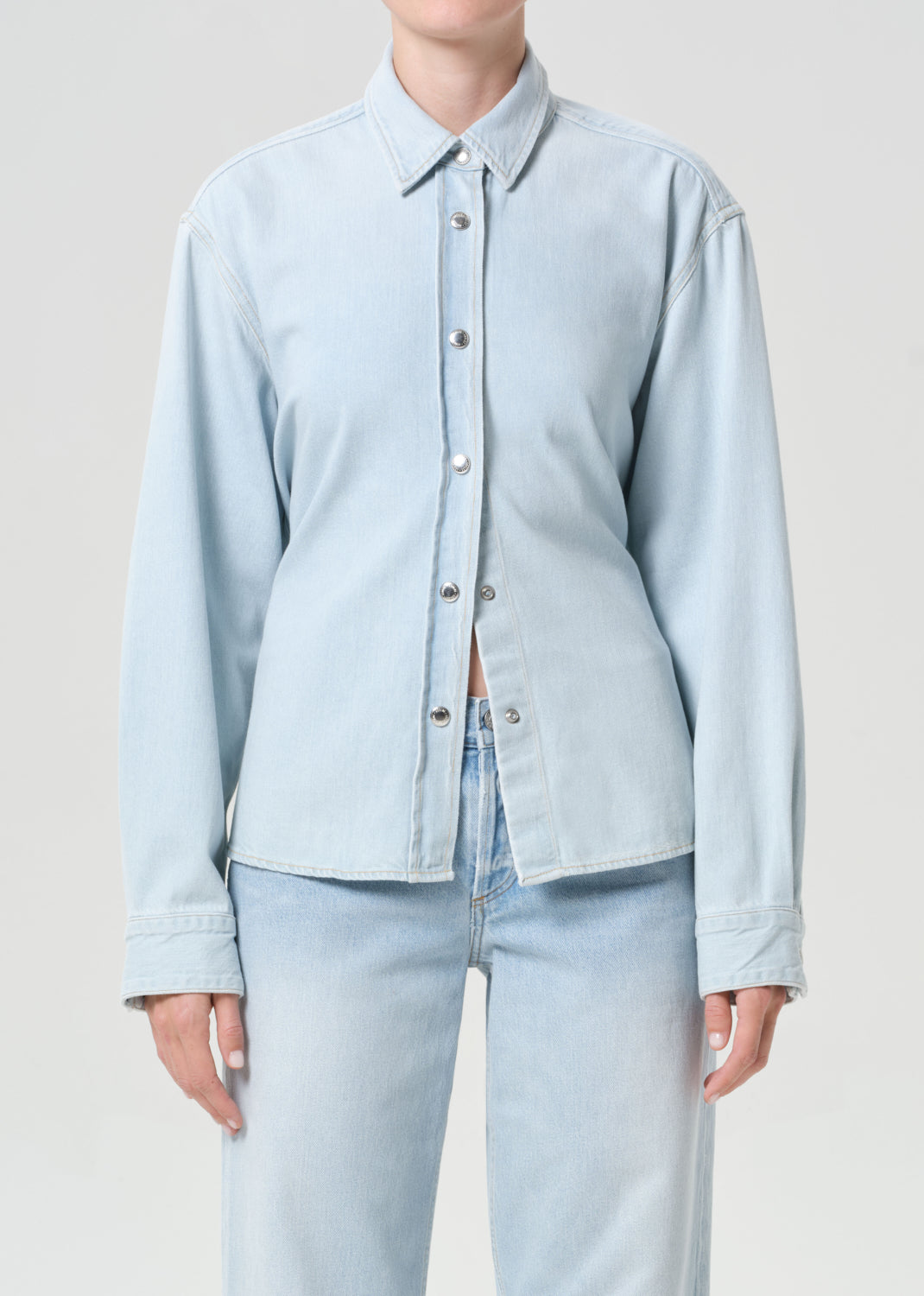 Light blue denim shirt worn by a person on a plain background