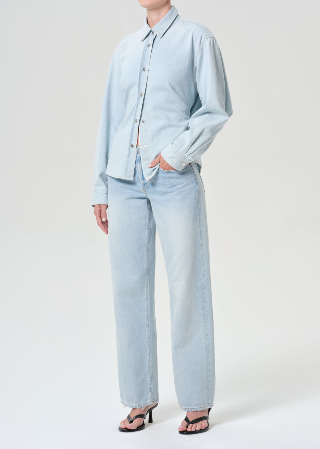 Person wearing a light blue shirt and pants on a white background