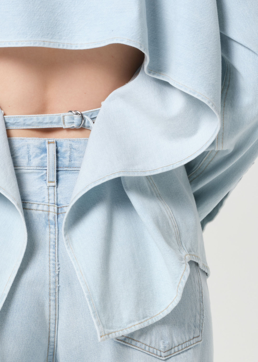 Light blue denim jacket over a light blue top on a neutral background