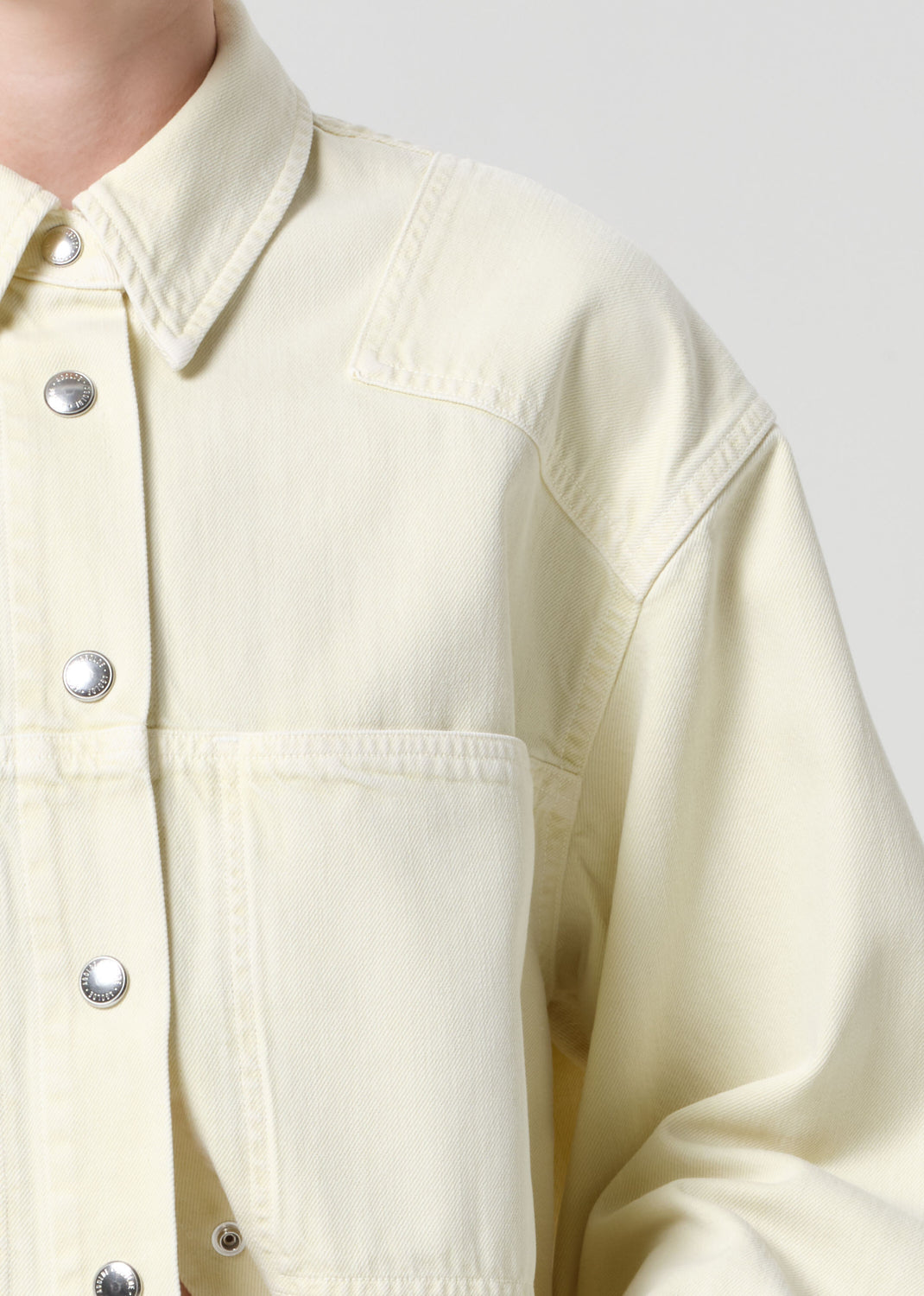 Light yellow denim jacket with button details on a white background