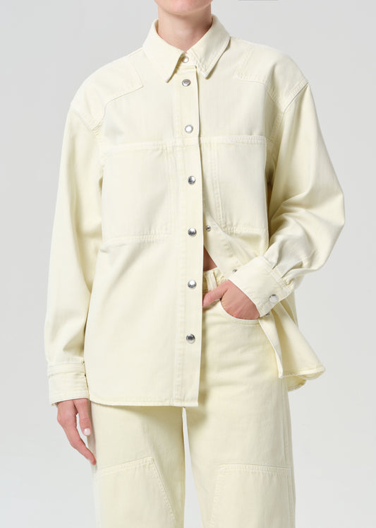 Person wearing a light yellow button-up shirt and pants on a plain background