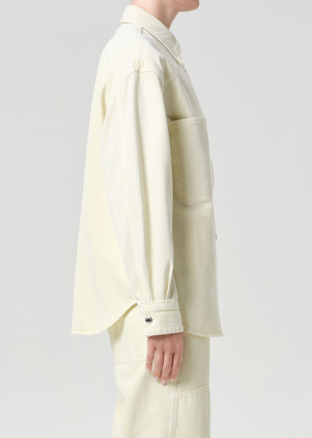 Person wearing a light-colored suit on a plain background