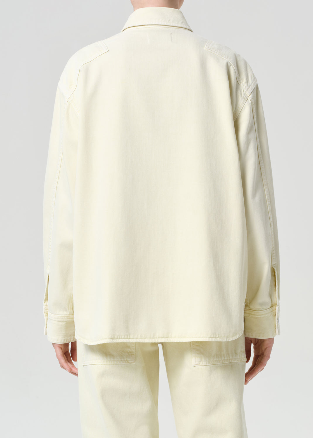 Person wearing a light-colored suit on a plain background