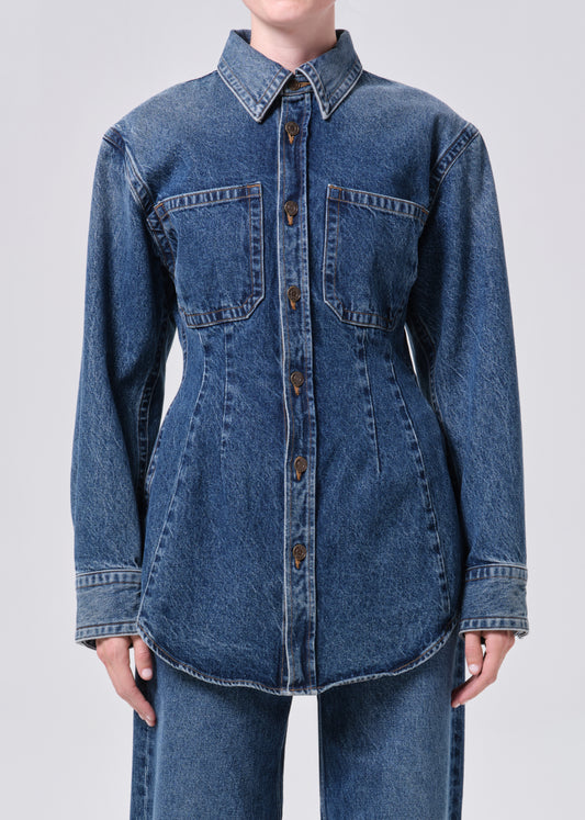 Blue denim shirt worn by a person on a light gray background