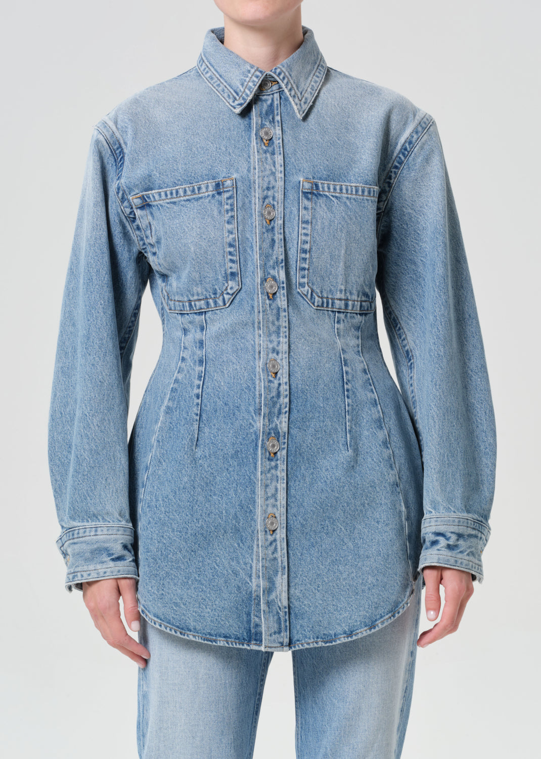 Light blue denim shirt worn by a person on a plain background