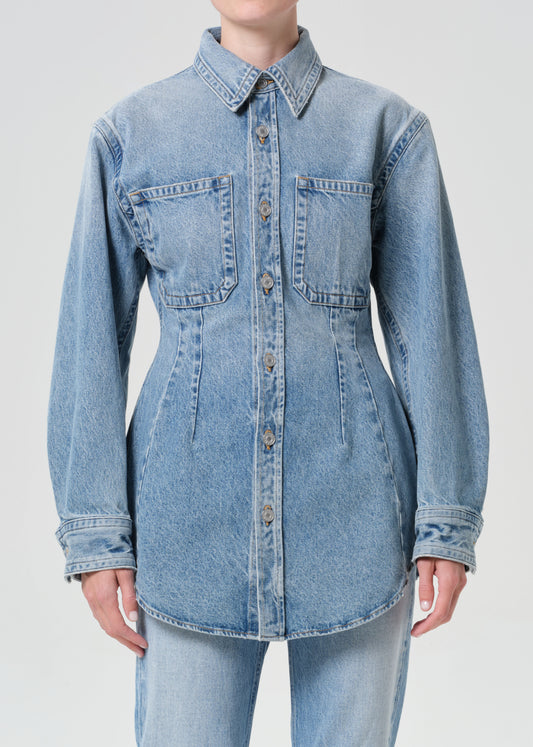 Light blue denim shirt worn by a person on a plain background