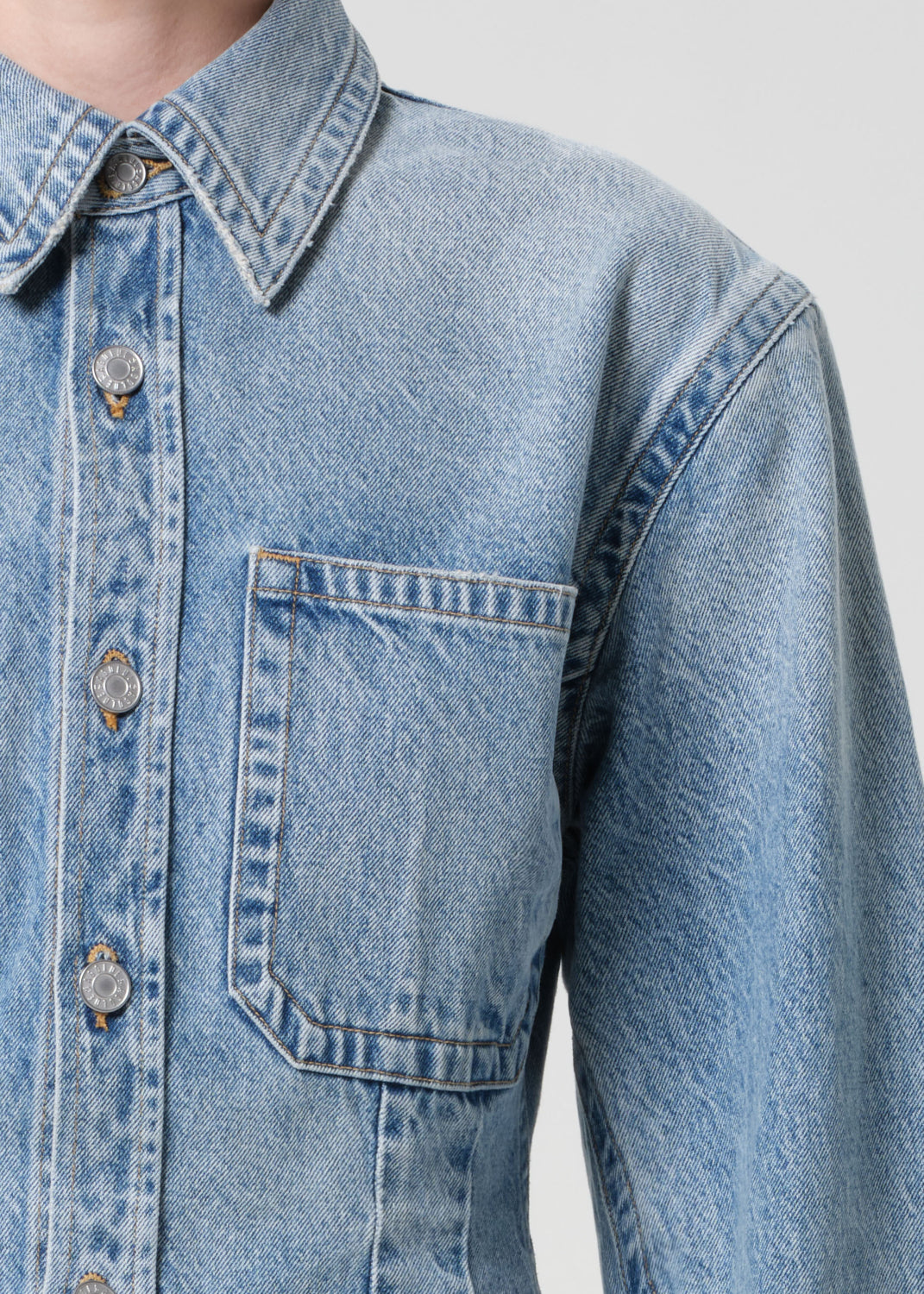 Close-up of a blue denim jacket with buttons on a plain background