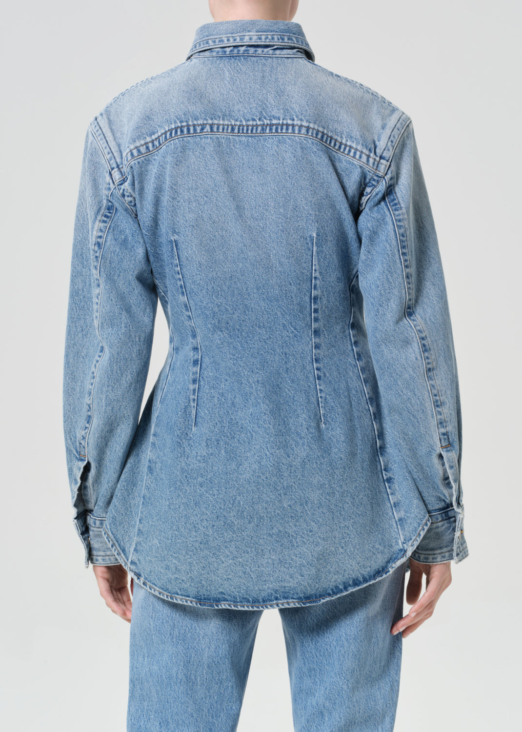 Light blue denim shirt worn by a person on a plain background