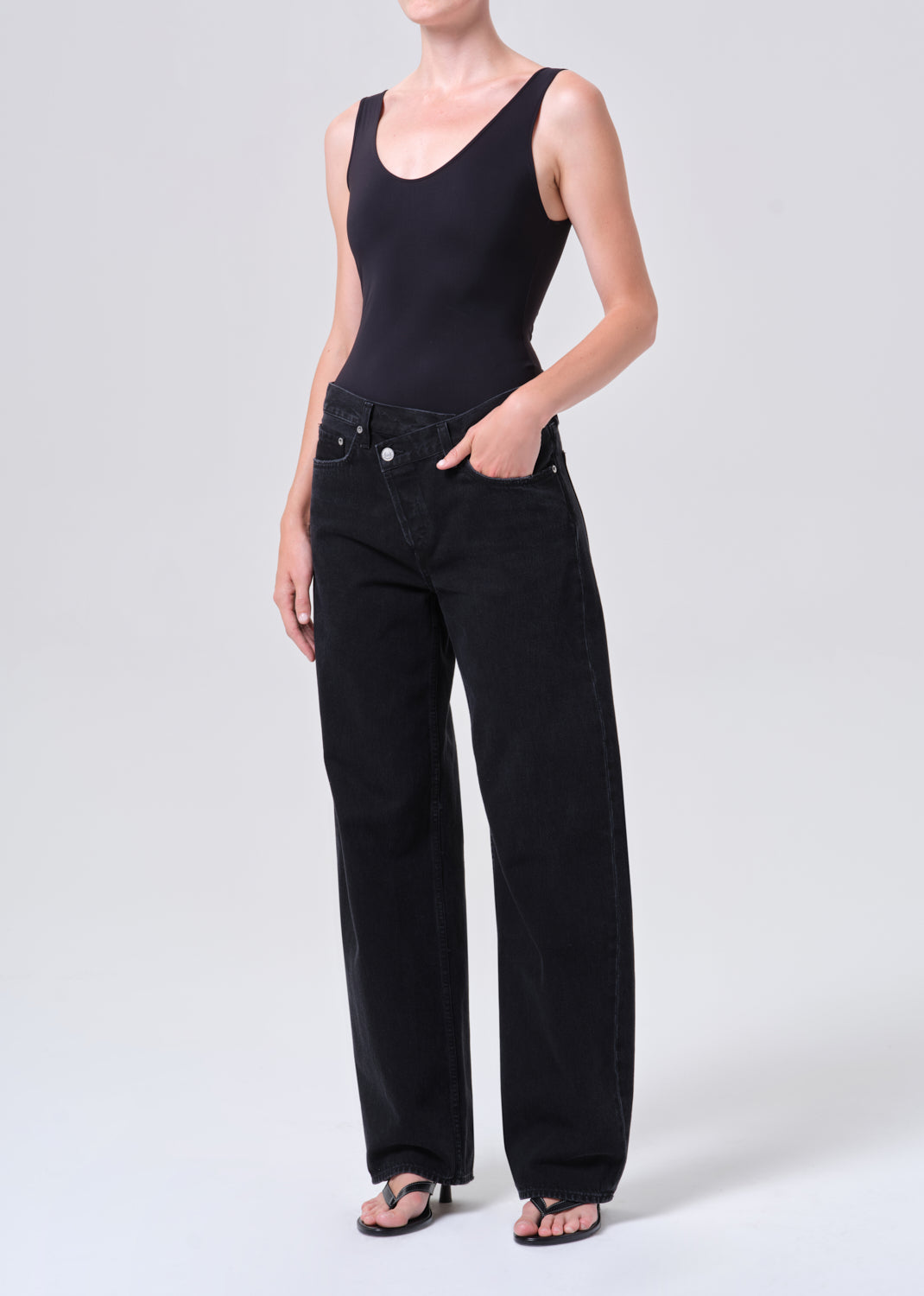 Person wearing a black tank top and black jeans on a white background