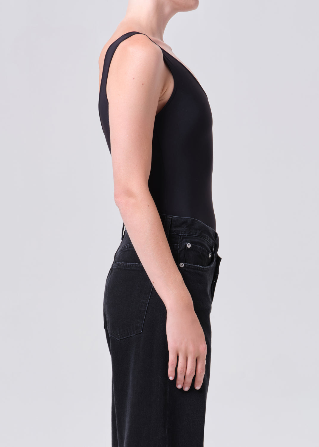 Person wearing a black sleeveless jumpsuit on a light gray background