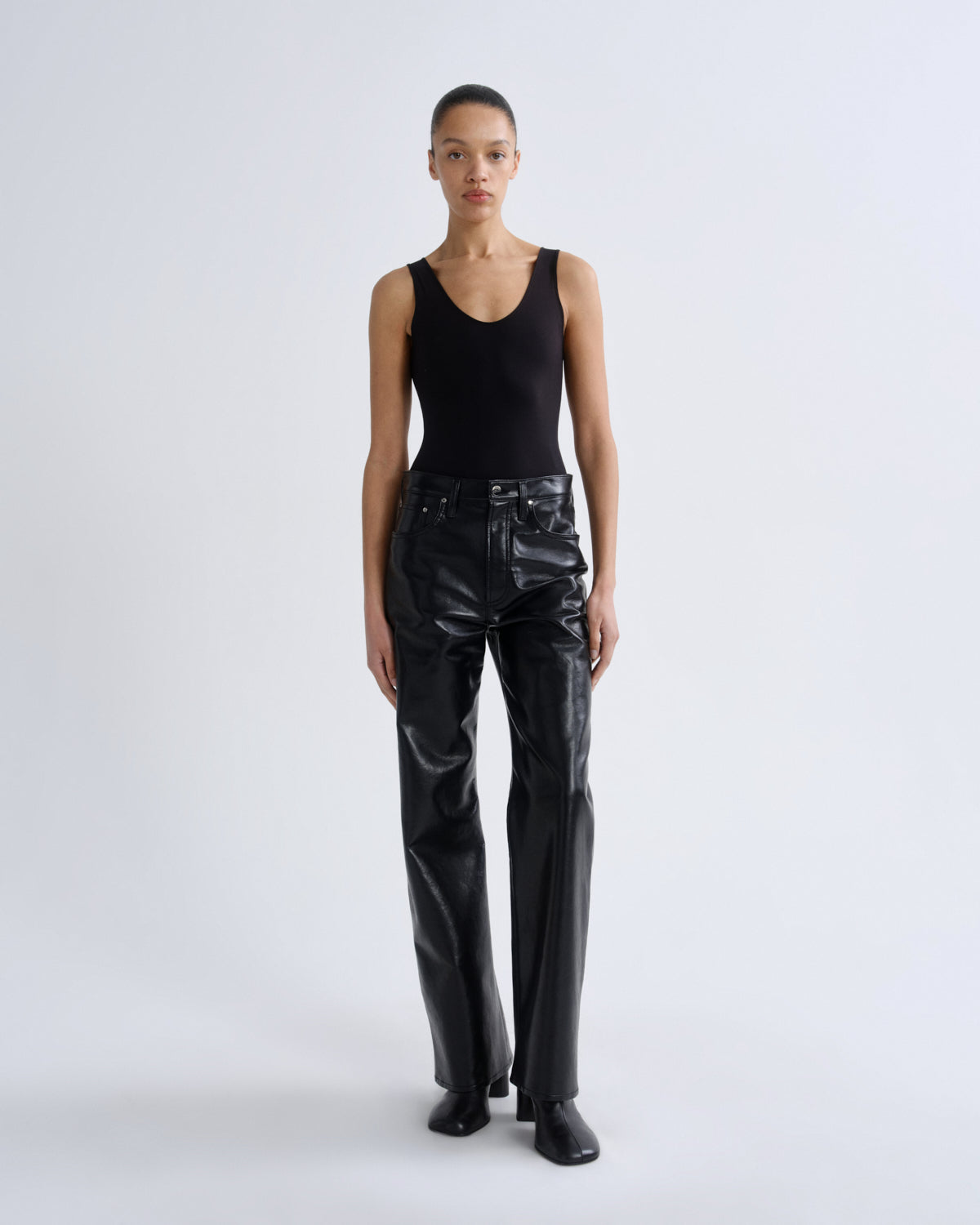 Person wearing a black tank top and black leather pants on a white background