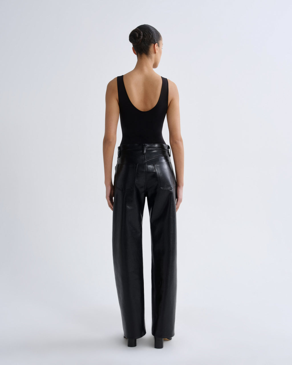 Person wearing black leather pants and a black tank top on a white background