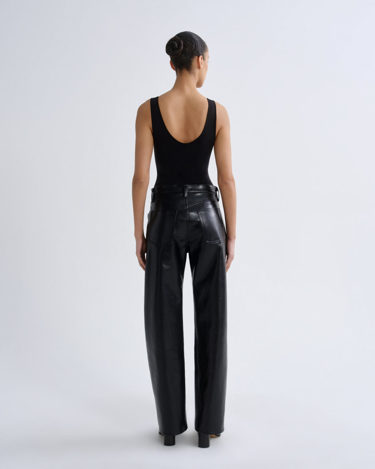 Person wearing black leather pants and a black tank top on a white background