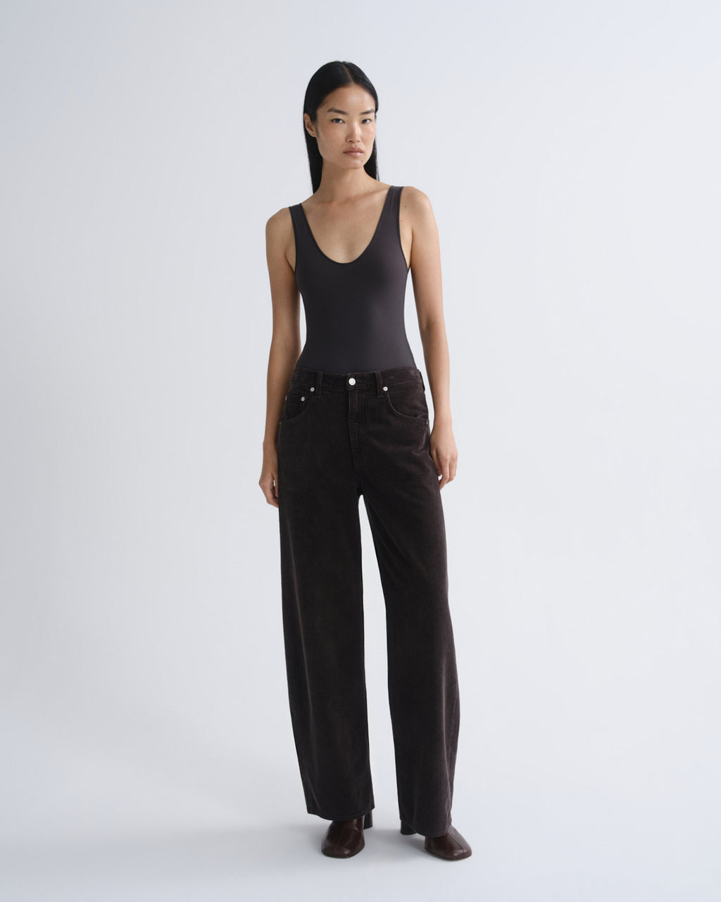 Woman wearing a black tank top and wide-leg pants on a white background