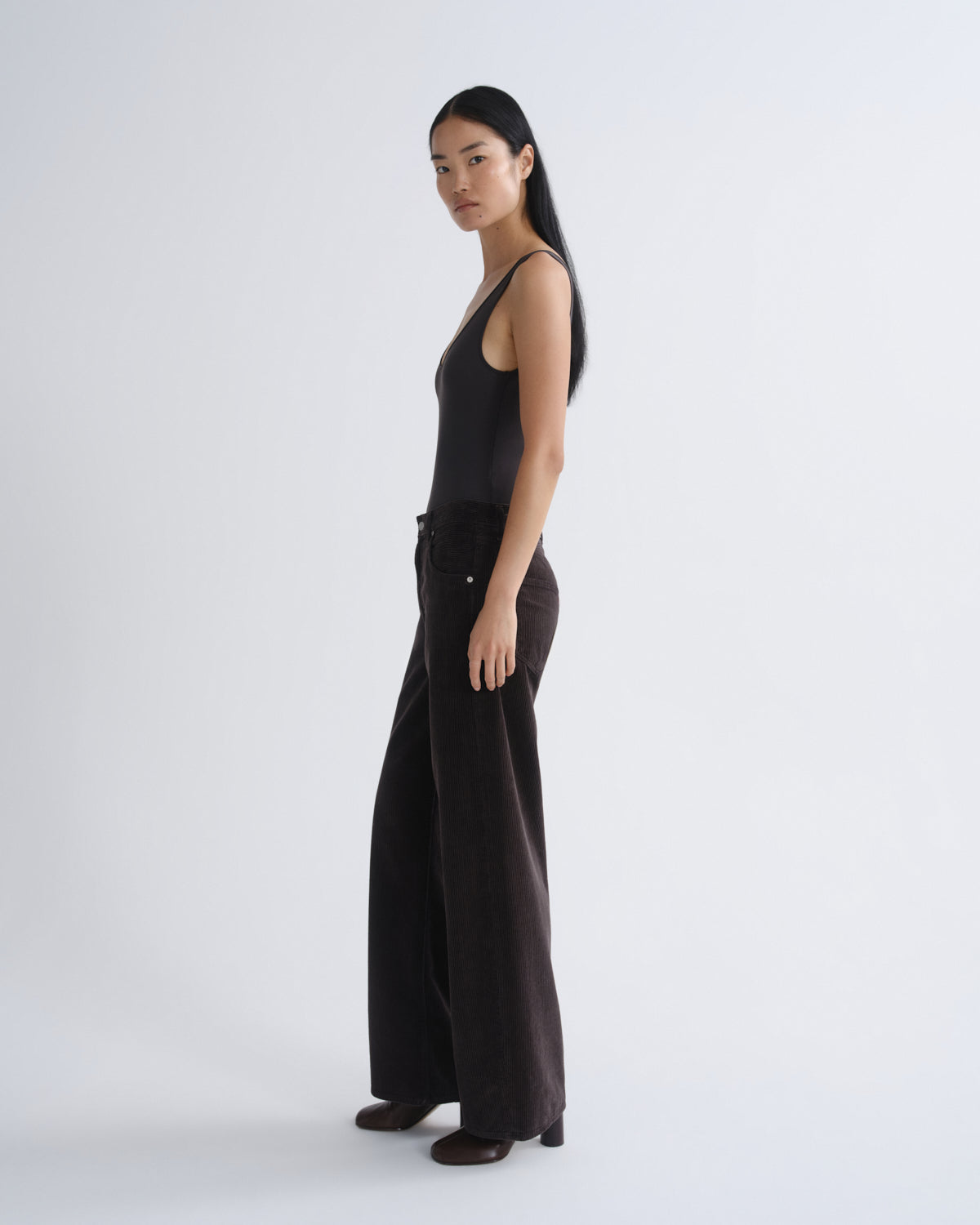 Woman wearing a black sleeveless top and wide-leg pants on a white background