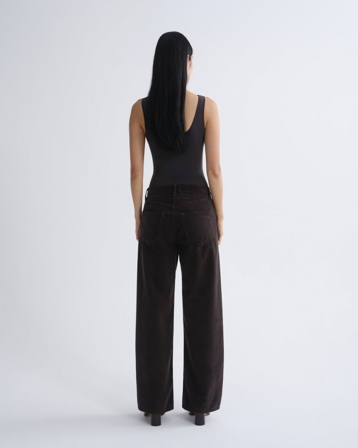 Person wearing a black sleeveless top and wide-leg pants on a white background