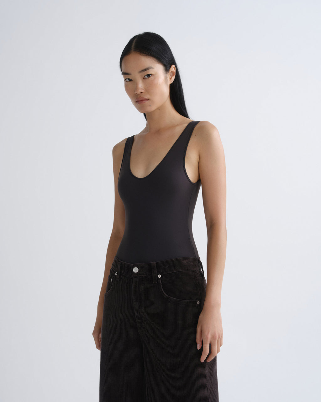 Woman wearing a black tank top and black pants on a white background