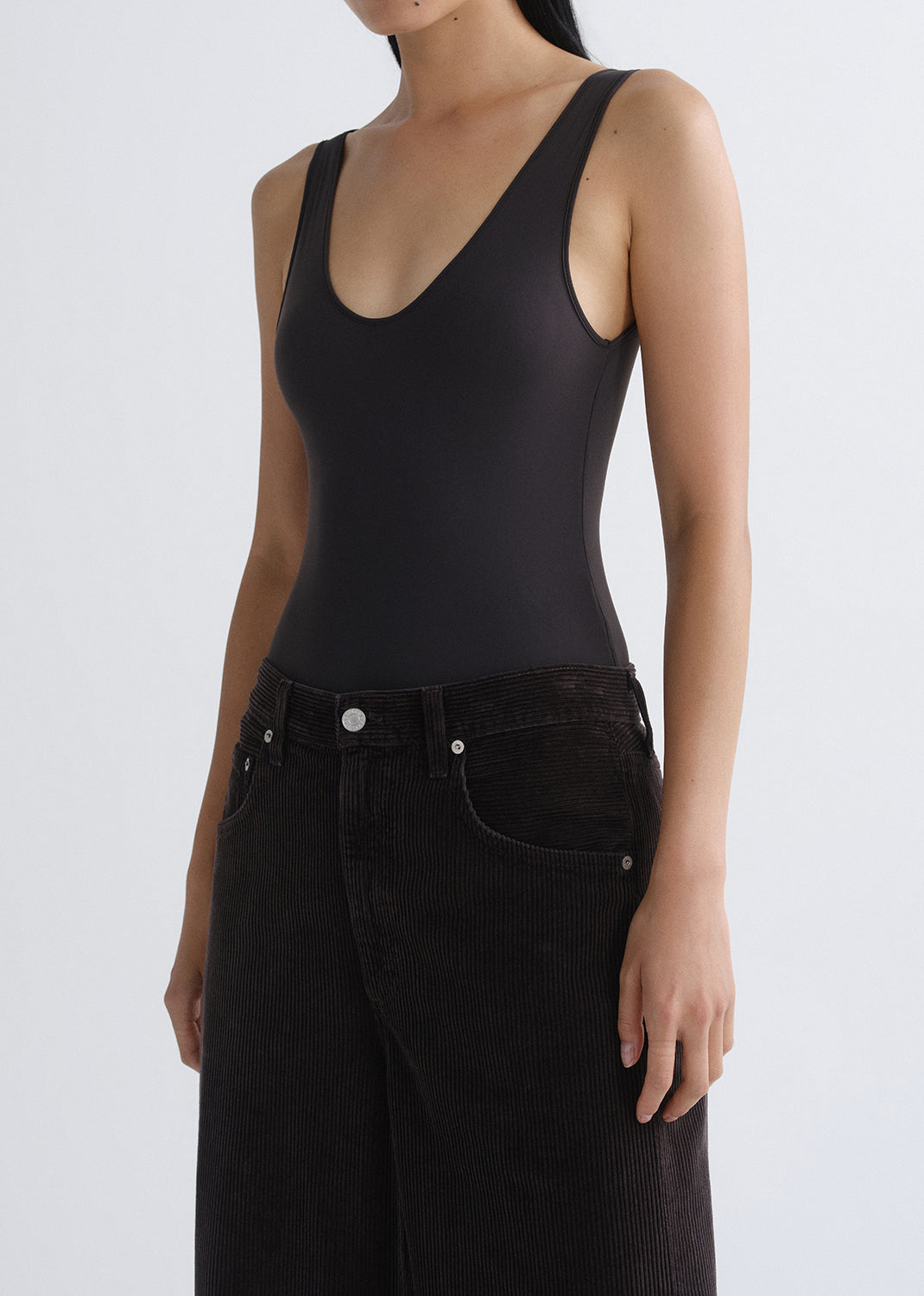 Person wearing a black tank top on a grey background