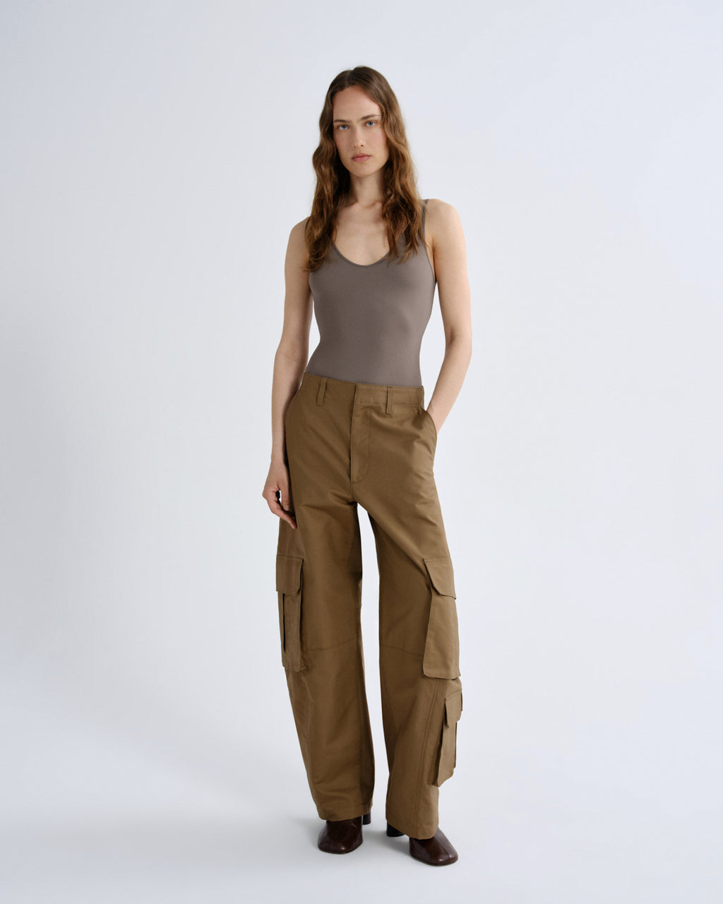 Woman wearing a brown tank top and cargo pants on a white background