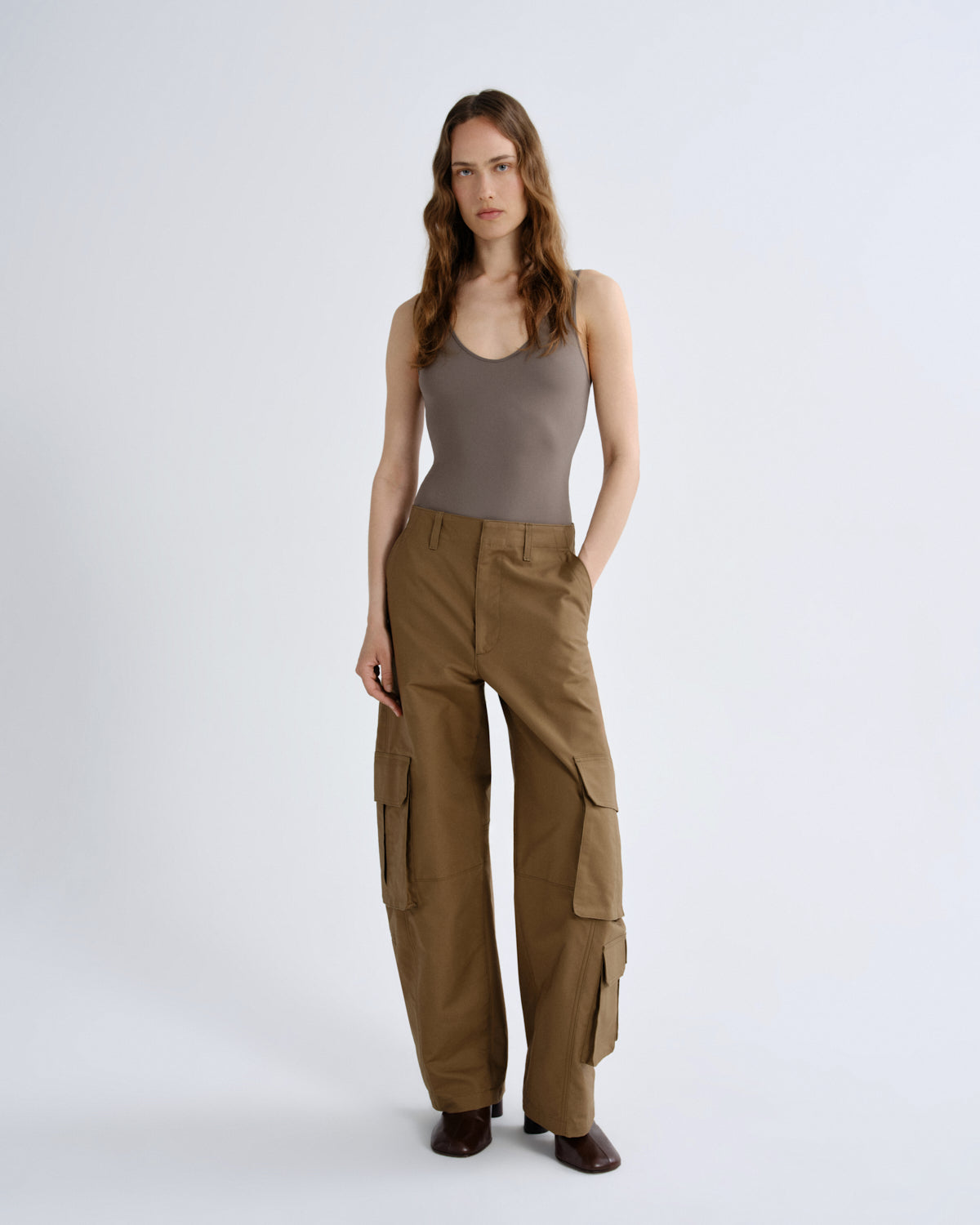 Woman wearing a brown tank top and cargo pants on a white background