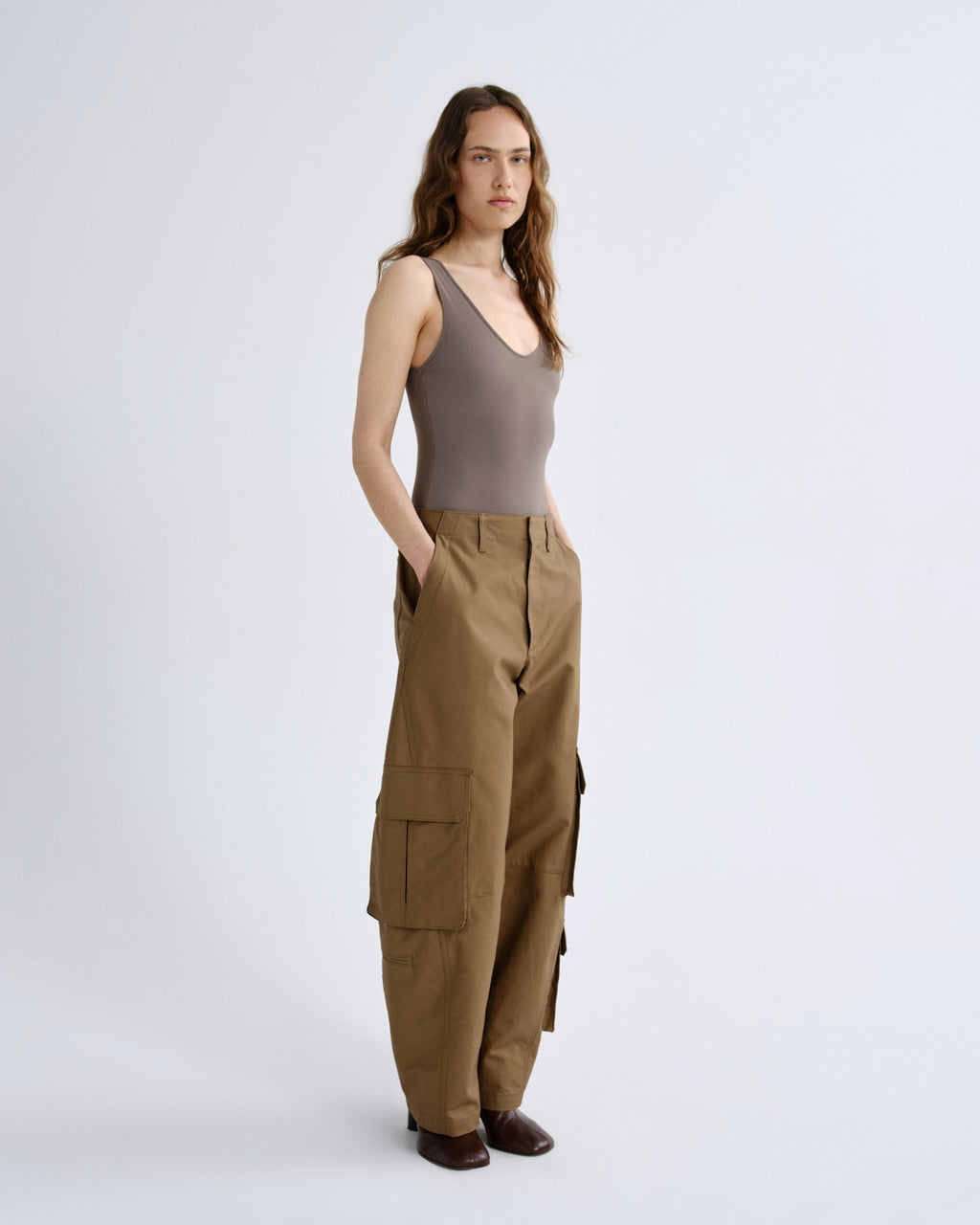 Woman wearing a brown tank top and cargo pants on a white background